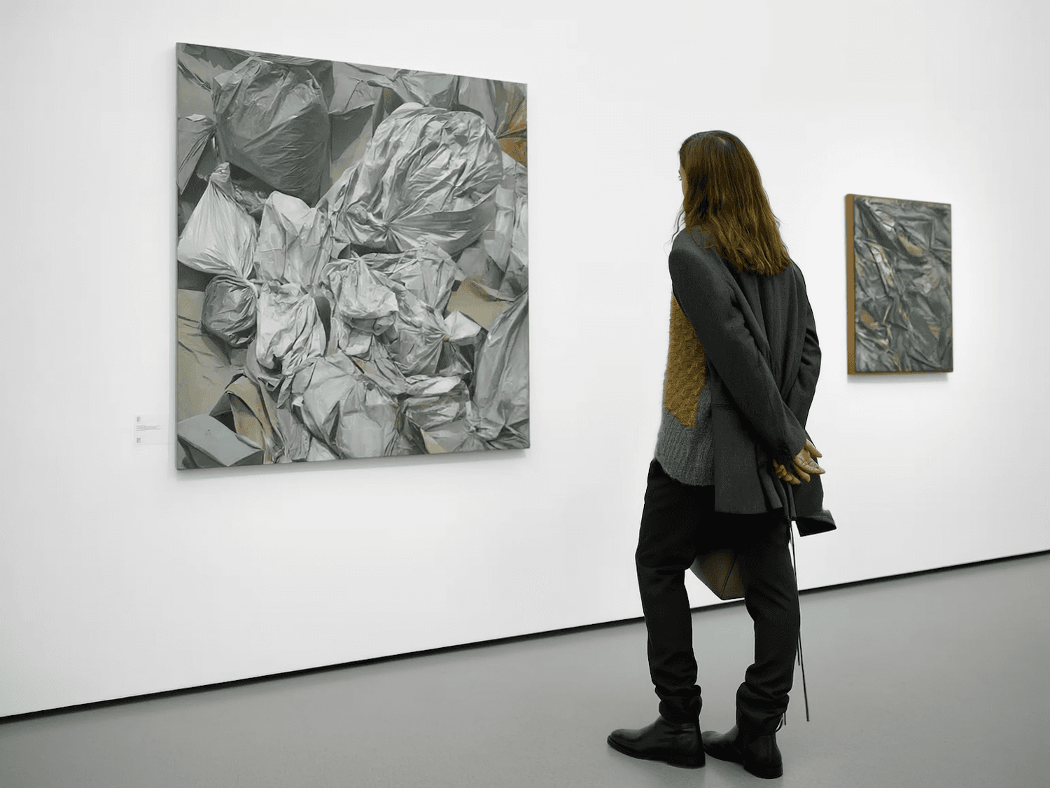 A visitor studying textured abstract paintings in a quiet gallery